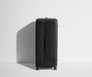 Side product view of The Trunk suitcase in Jet Black to show the slimmer top lid and deeper main compartment for easy access and packing