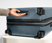 The Large Flex suitcase in Coast Blue shown from below highlighting the underside grab handle