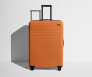 Front product view of The Large suitcase in Sorbet Orange with raised handle