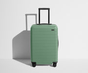Front product view of The Bigger Carry-On suitcase in Sea Green with raised handle