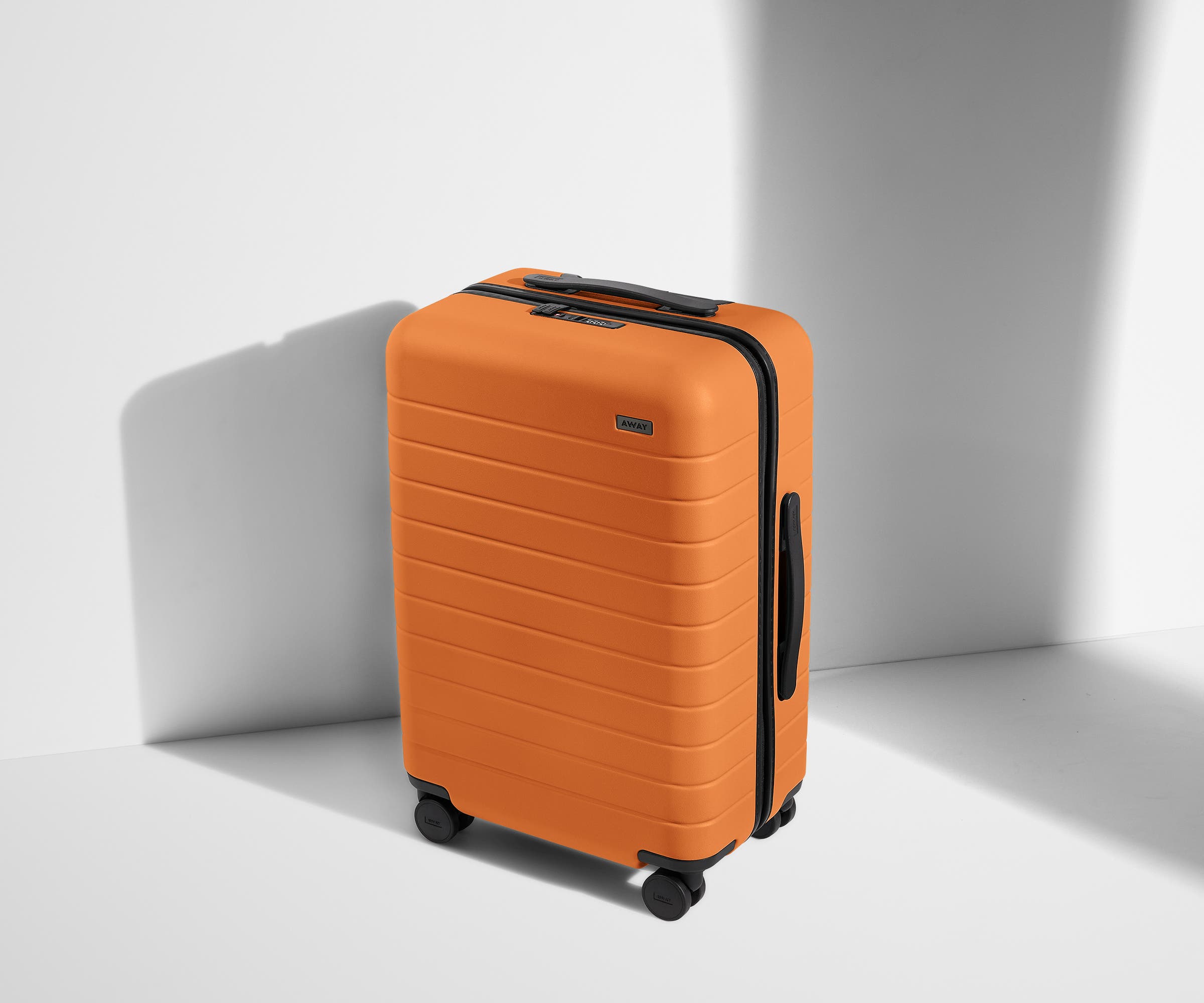 Angled product view of The Bigger Carry-On suitcase in Sorbet Orange