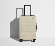 Front product view of The Bigger Carry-On suitcase in Salt White (Gloss) with raised handle