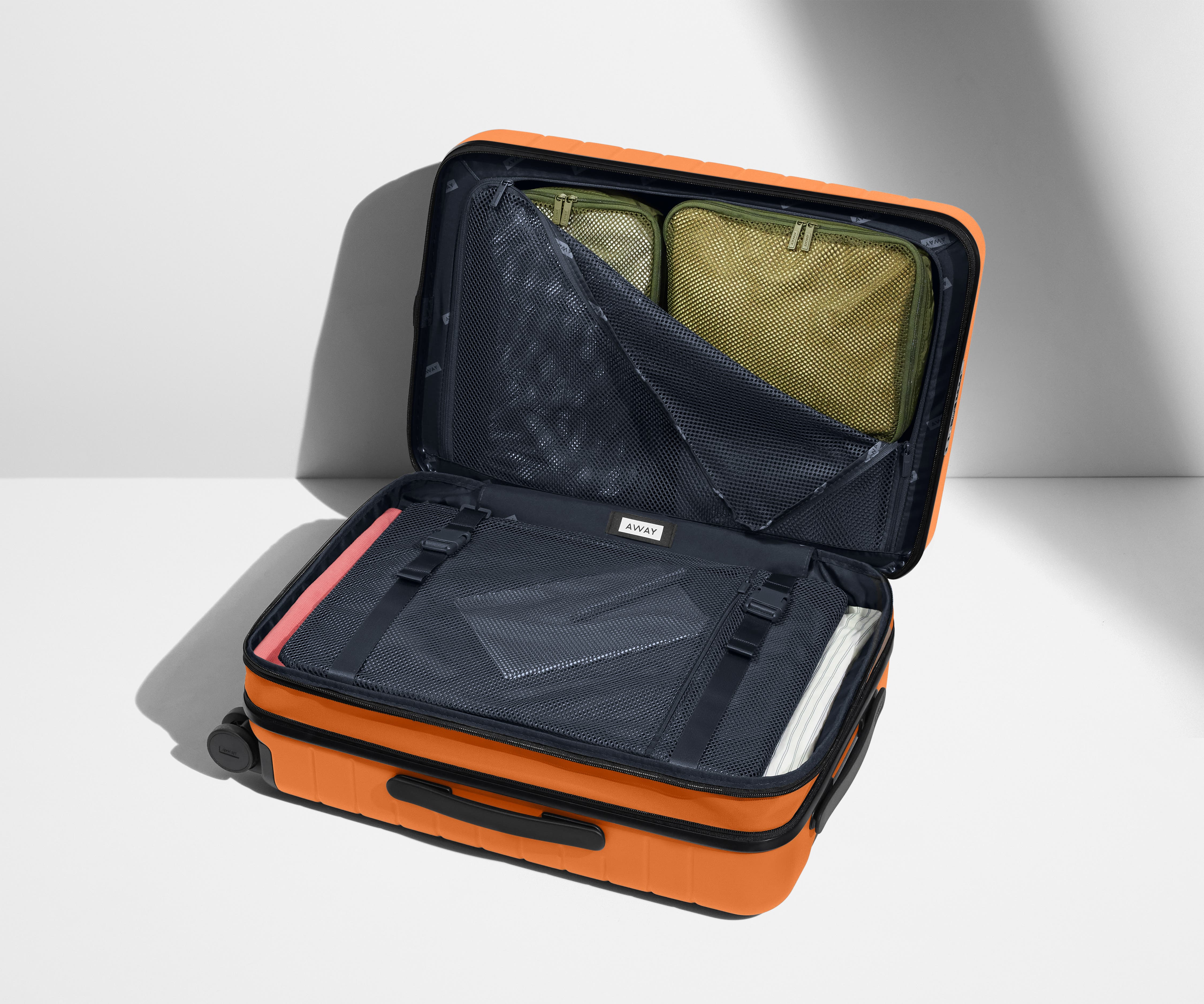 The Carry-On Flex suitcase shown open on its side and packed with Away's packing organizers to show capacity and the interior compression system, designed to help you pack more in