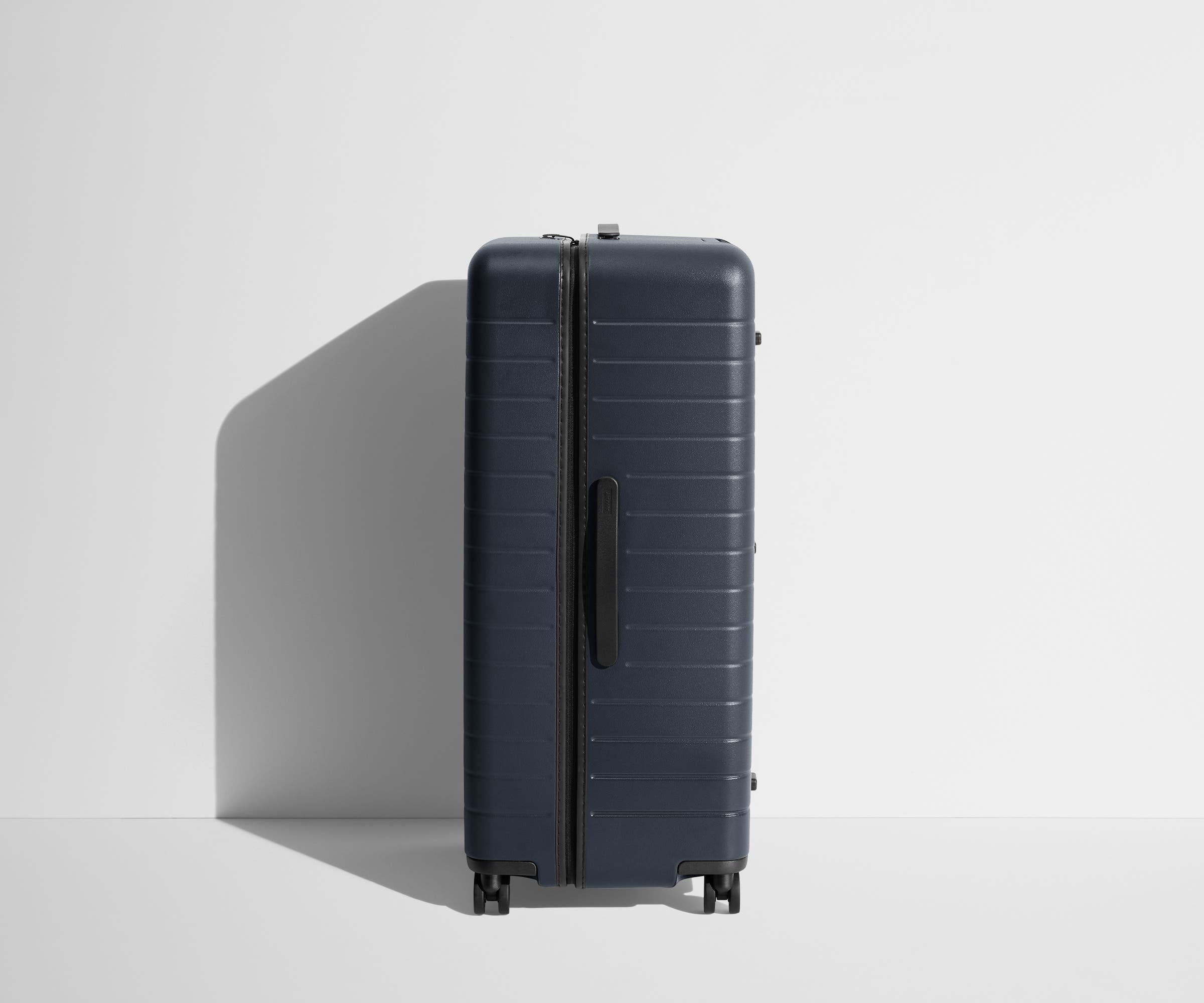 Side product view of The Trunk suitcase in Navy Blue to show the slimmer top lid and deeper main compartment for easy access and packing