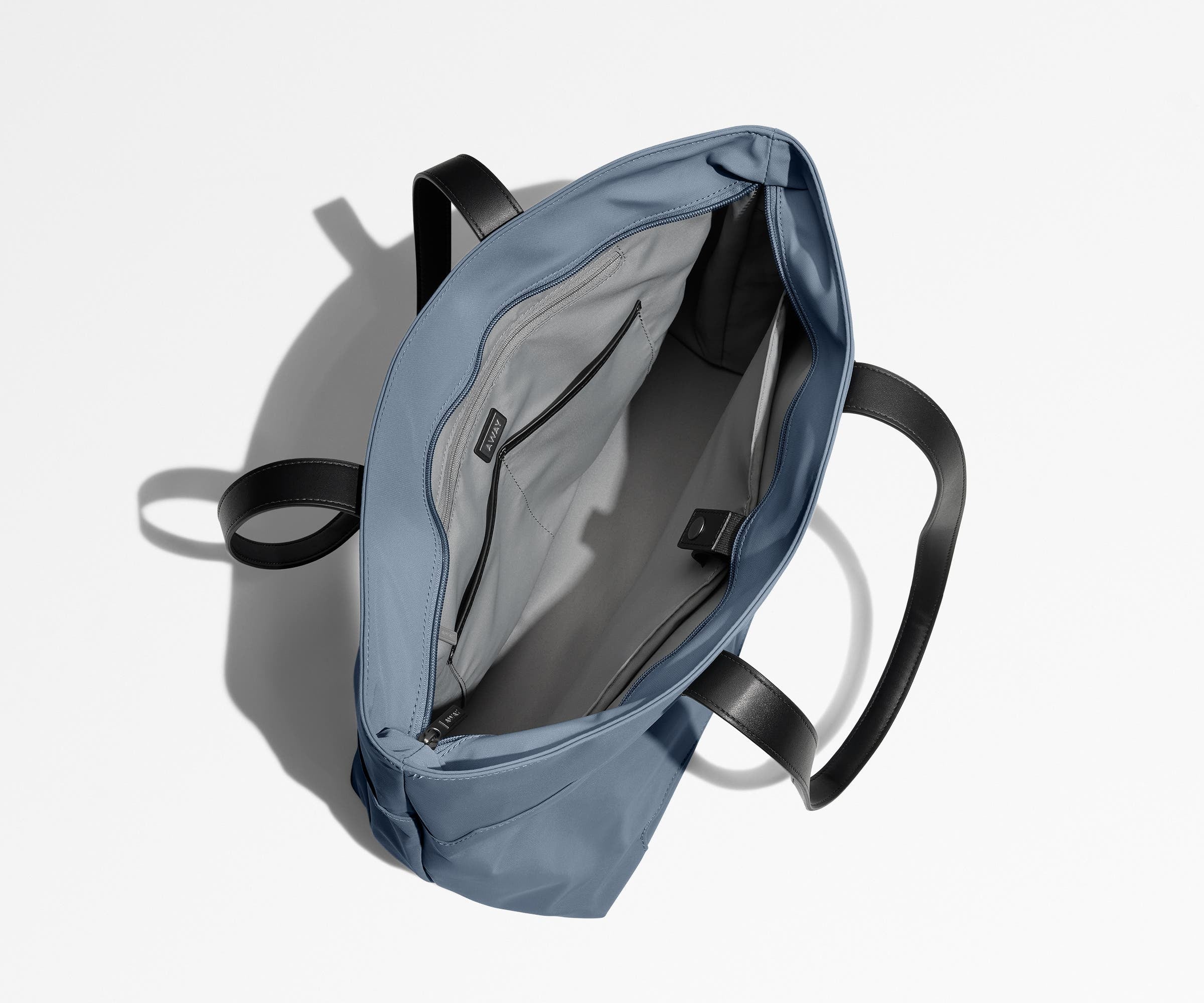 Unzipped and unpacked Everywhere Tote bag, showing the interior zip pockets, slip pockets, and laptop pocket