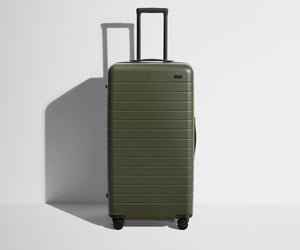 Front product view of The Trunk suitcase in Olive Green with raised handle