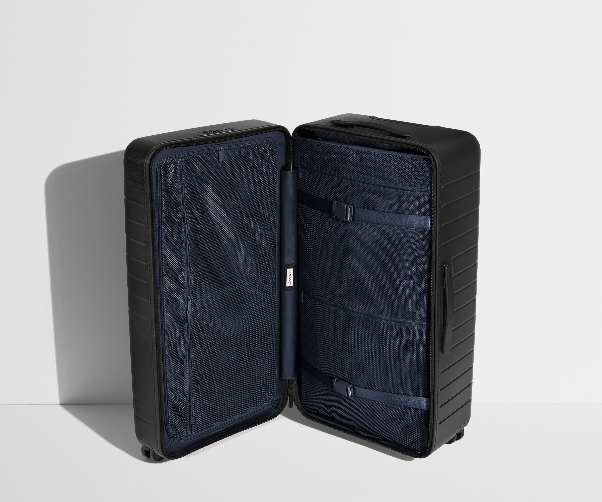 The Trunk suitcase in Jet Black shown open in an upright position to show interior organization and compression system