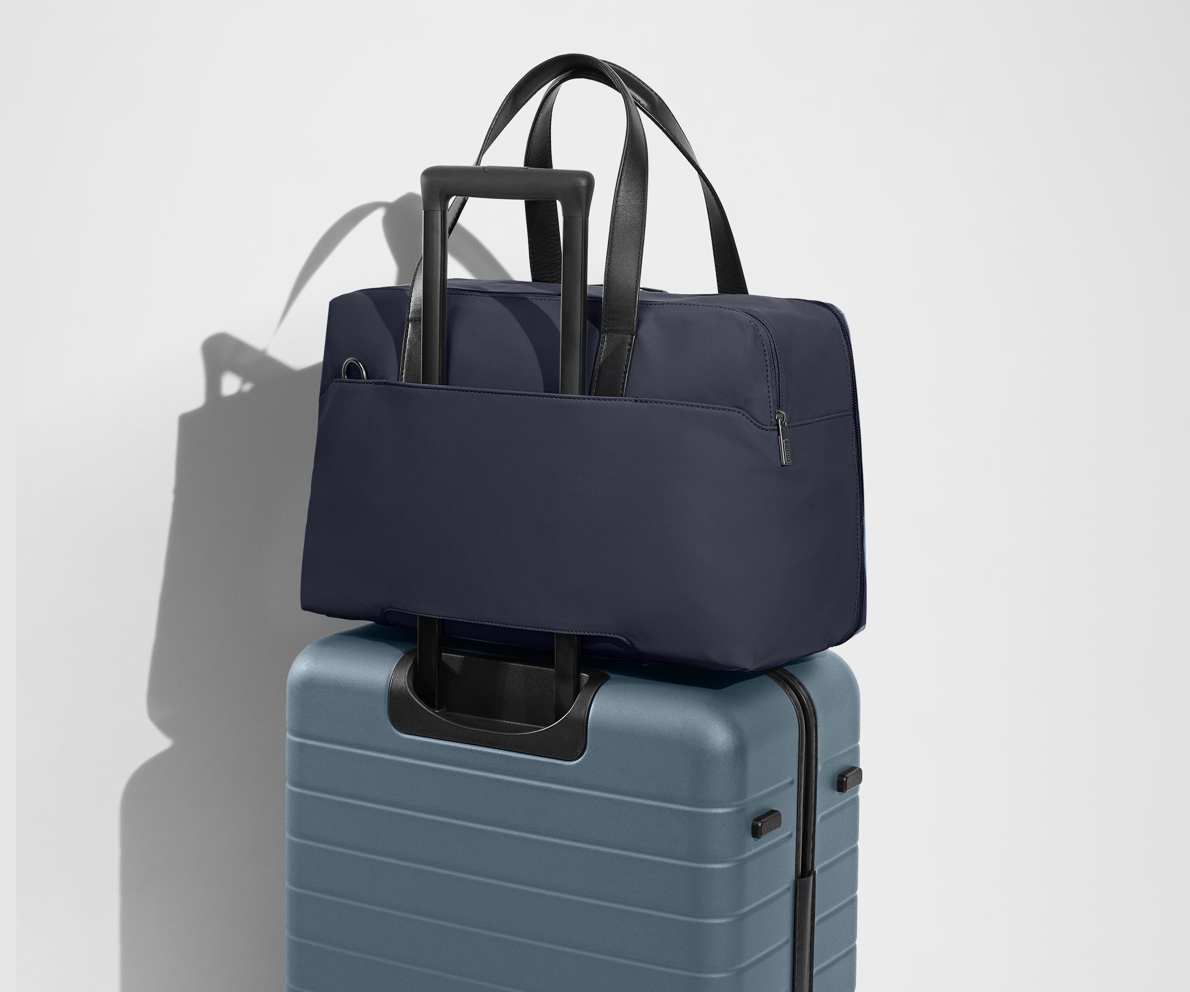 The Overnight Bag secured to an Away checked suitcase using the trolley sleeve