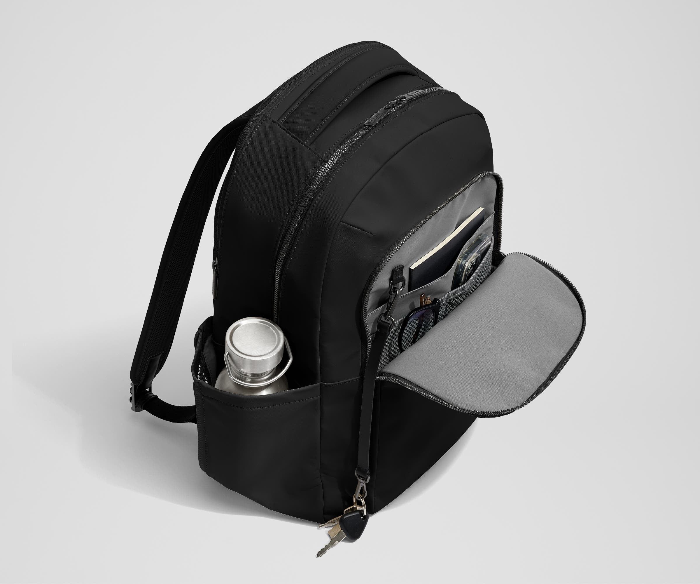 Front exterior zip pocket, detachable key clip, and exterior water bottle pocket of The Commuter Backpack