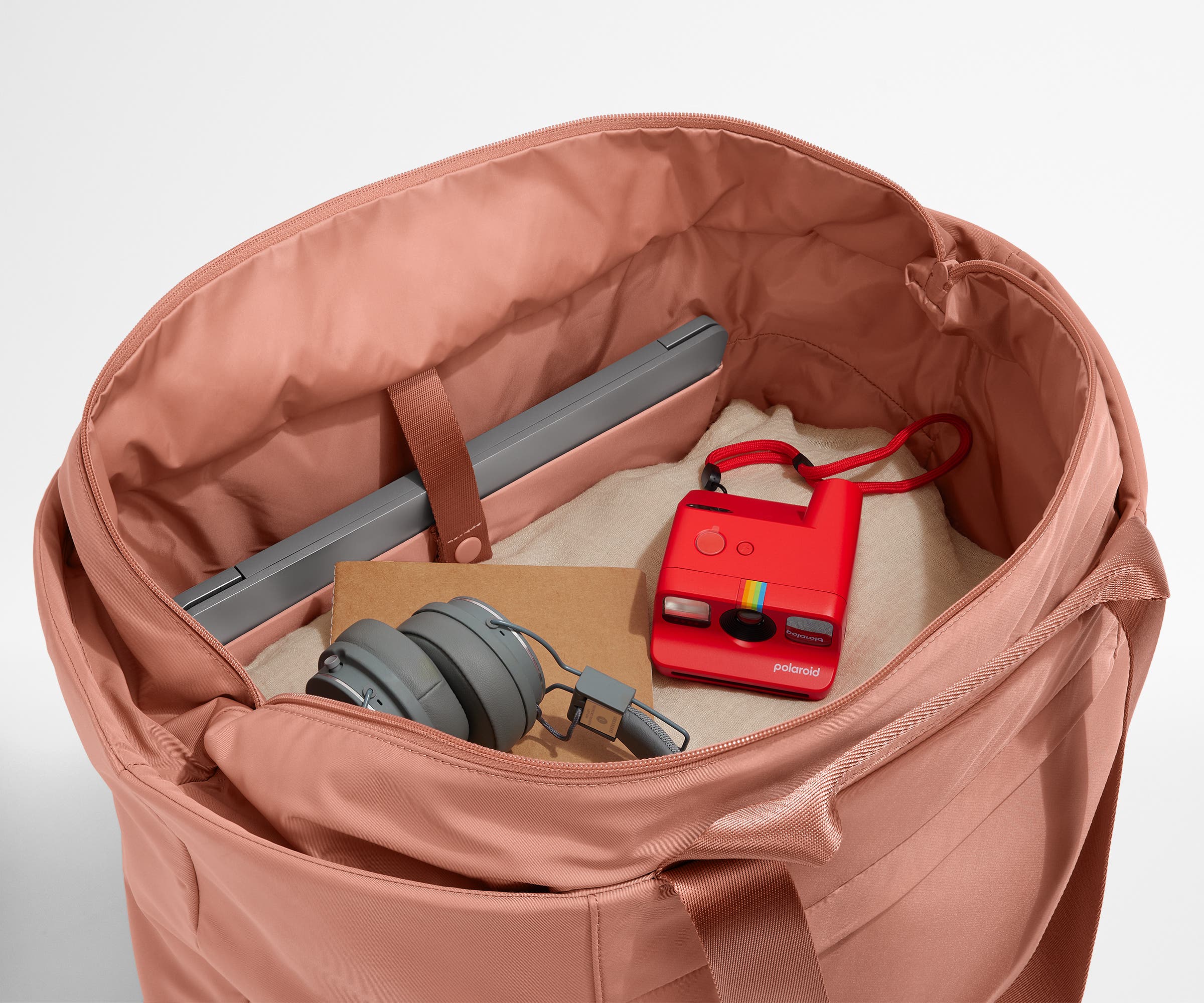 Interior packed with clothing, a laptop, headphones, notebook, and camera