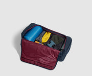 85L rolling duffle bag packed with a sleeping bag, outdoor gear, and clothing