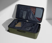 The Trunk suitcase in Olive Green shown open on its side and packed with Away's packing organizers to show capacity and the interior compression system, designed to help you pack more in