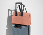 The Everywhere Bag secured to an Away suitcase by its trolley sleeve