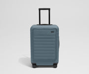 Front product view of The Front Pocket Bigger Carry-On suitcase in Coast Blue with raised handle
