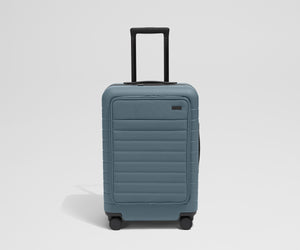 Front product view of The Front Pocket Bigger Carry-On suitcase in Coast Blue with raised handle
