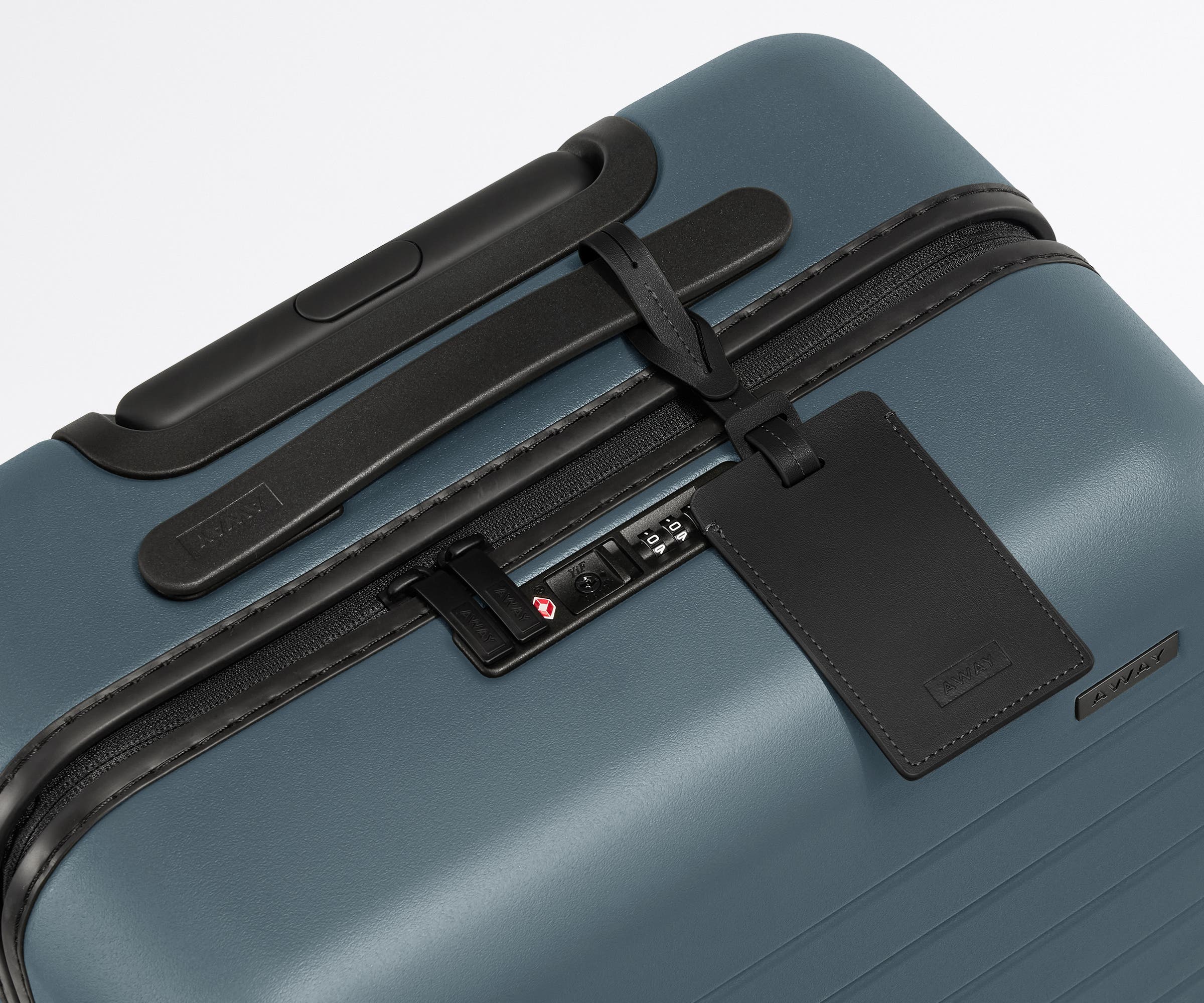 The Carry-On suitcase in Coast Blue shown shown from above highlighting TSA-approved combination lock and recycled leather luggage tag