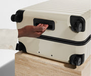 The Large suitcase in Salt White (Gloss) shown from below highlighting the underside grab handle