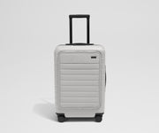 Front product view of The Front Pocket Bigger Carry-On suitcase in Cloud Gray with raised handle