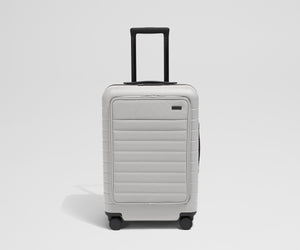 Front product view of The Front Pocket Bigger Carry-On suitcase in Cloud Gray with raised handle