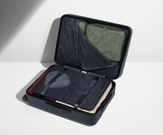 The Medium suitcase in Coast Blue shown open on its side and packed with Away's packing organizers to show capacity and the interior compression system, designed to help you pack more in