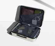 The Carry-On suitcase in Coast Blue shown open on its side and packed with Away's packing organizers to show capacity and the interior compression system, designed to help you pack more in