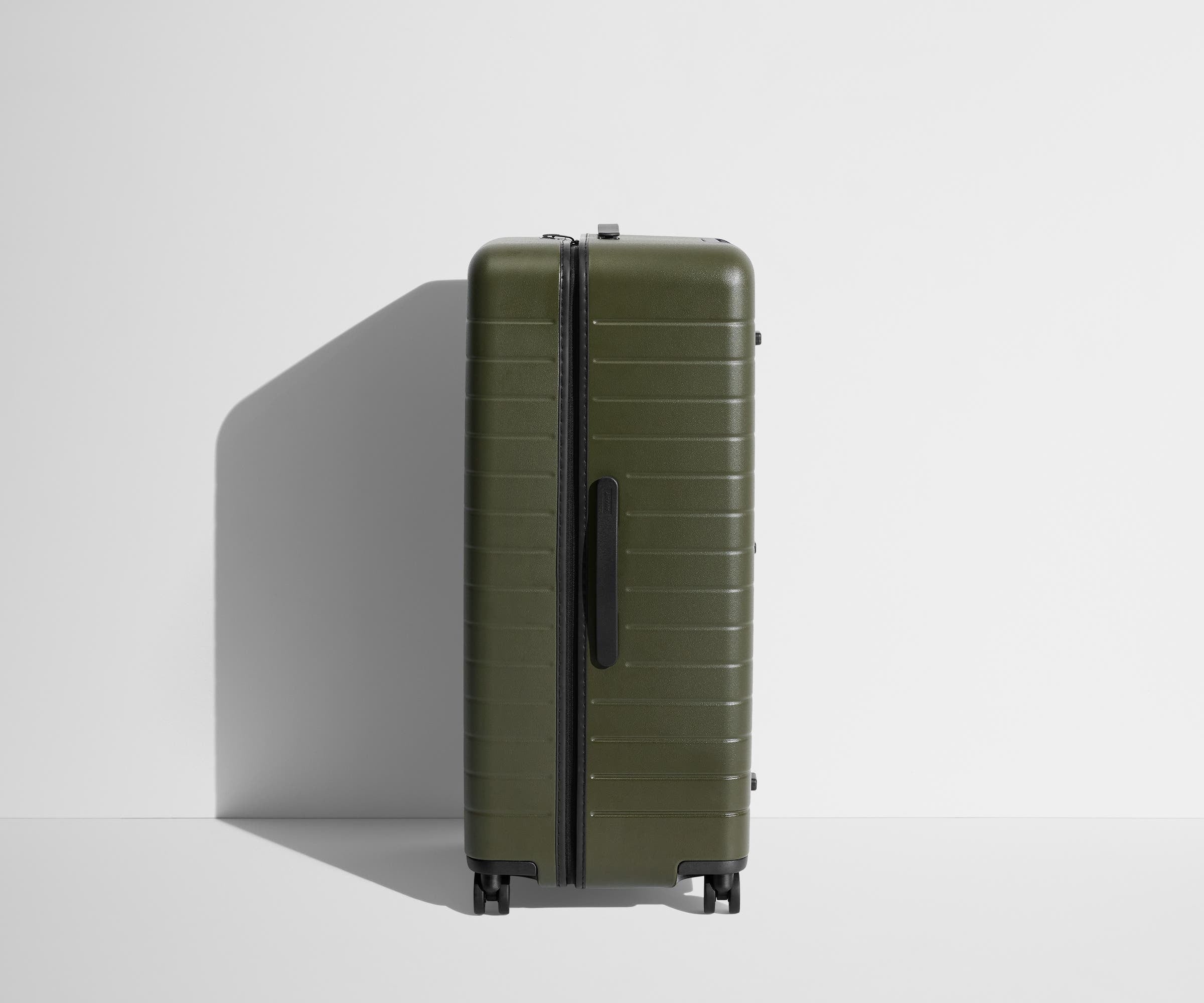 Side product view of The Trunk suitcase in Olive Green to show the slimmer top lid and deeper main compartment for easy access and packing