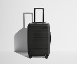 Front product view of The Carry-On suitcase in Jet Black with raised handle