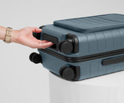 The Front Pocket Carry-On suitcase in Coast Blue shown from below highlighting the underside grab handle