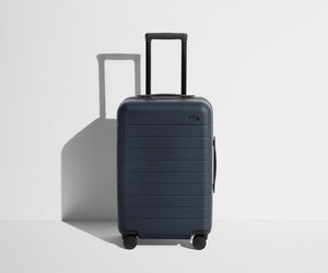 Front product view of The Carry-On suitcase in Navy Blue with raised handle
