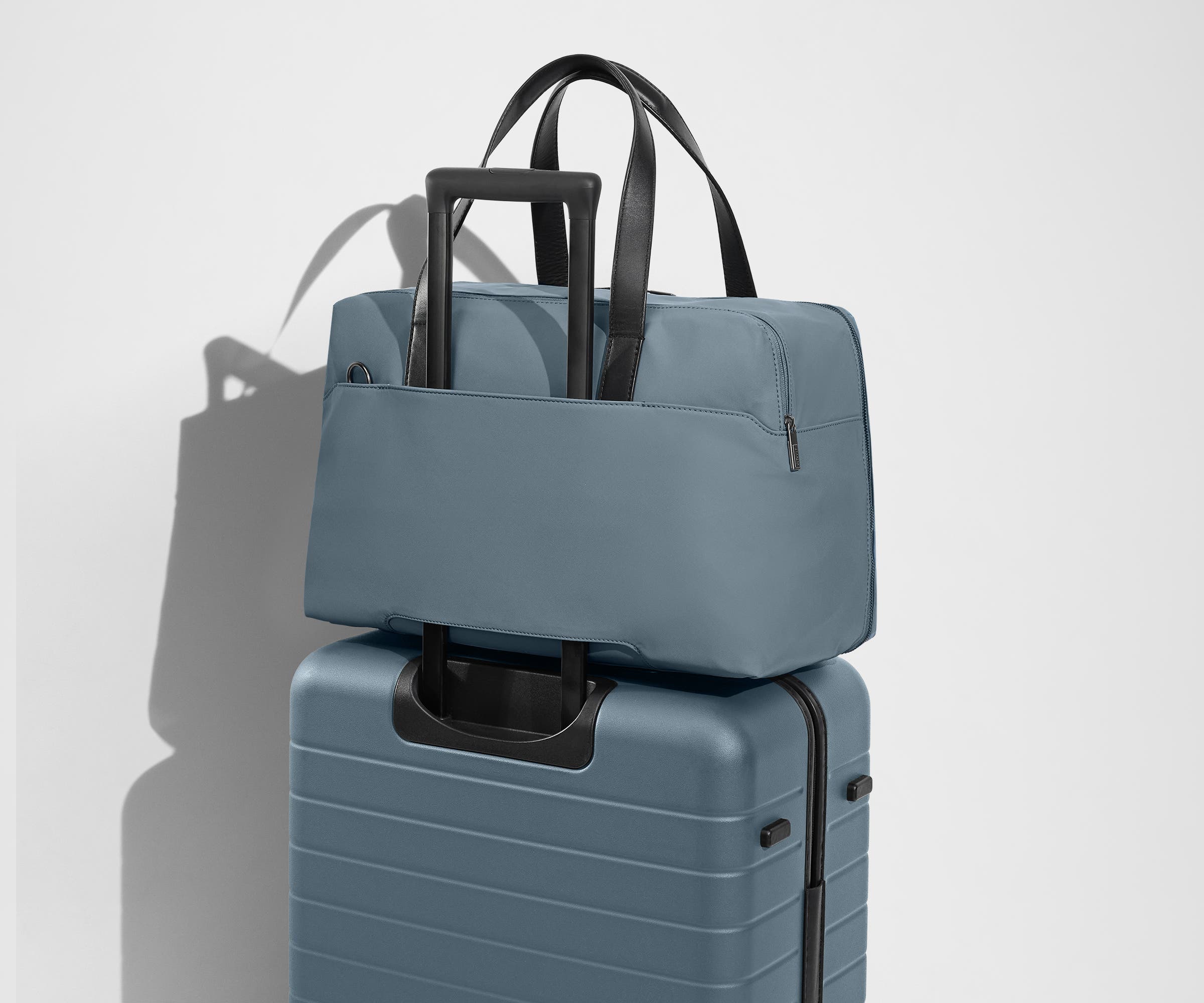 The Overnight Bag secured to an Away checked suitcase using the trolley sleeve