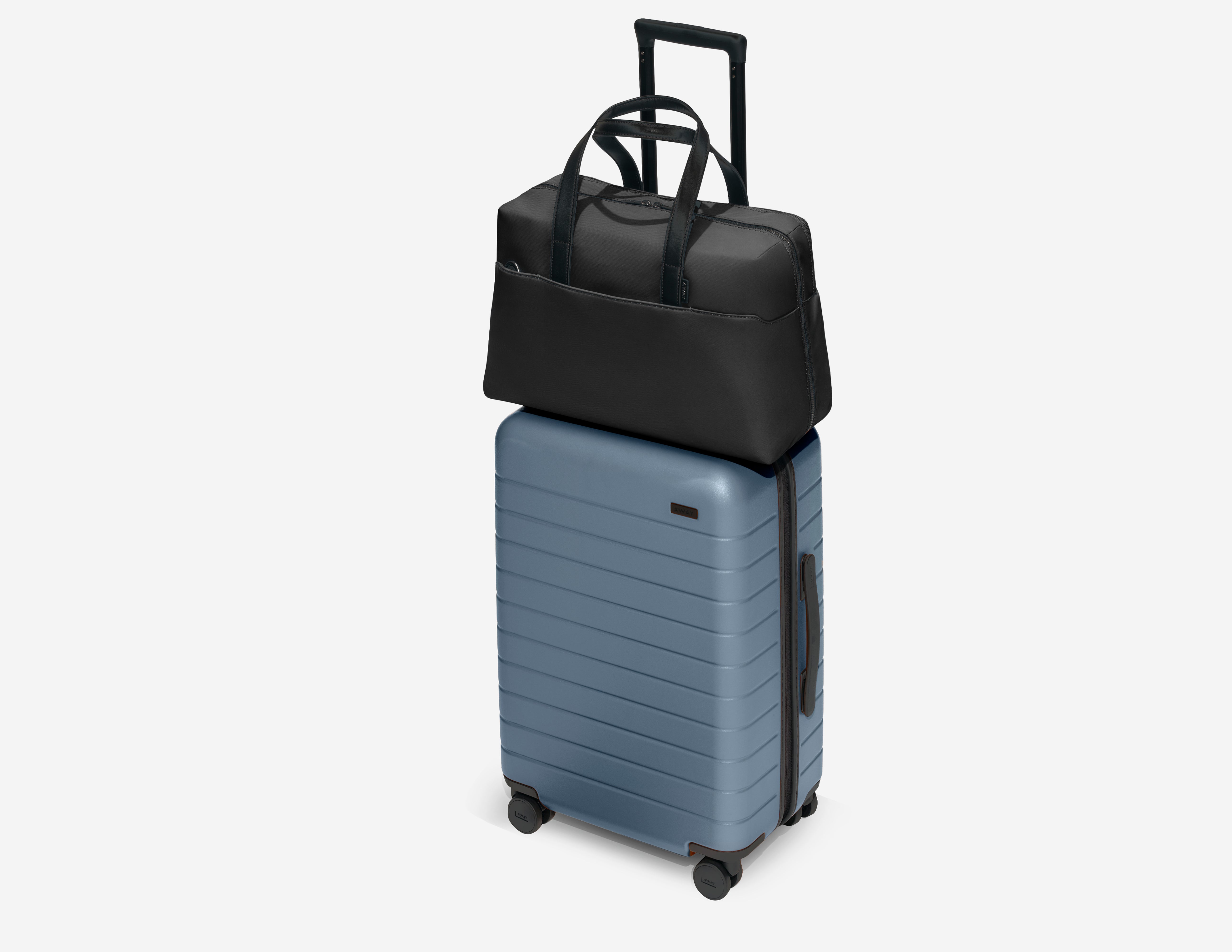 A Black Everywhere Bag atop a Coast Blue Bigger Carry-On suitcase
