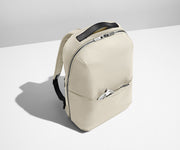 Angled product view of a Salt White Zip Backpack with a charging cord packed in the exterior front pocket