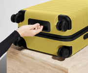 The Bigger Carry-On suitcase in Sunshine Yellow shown from below highlighting the underside grab handle