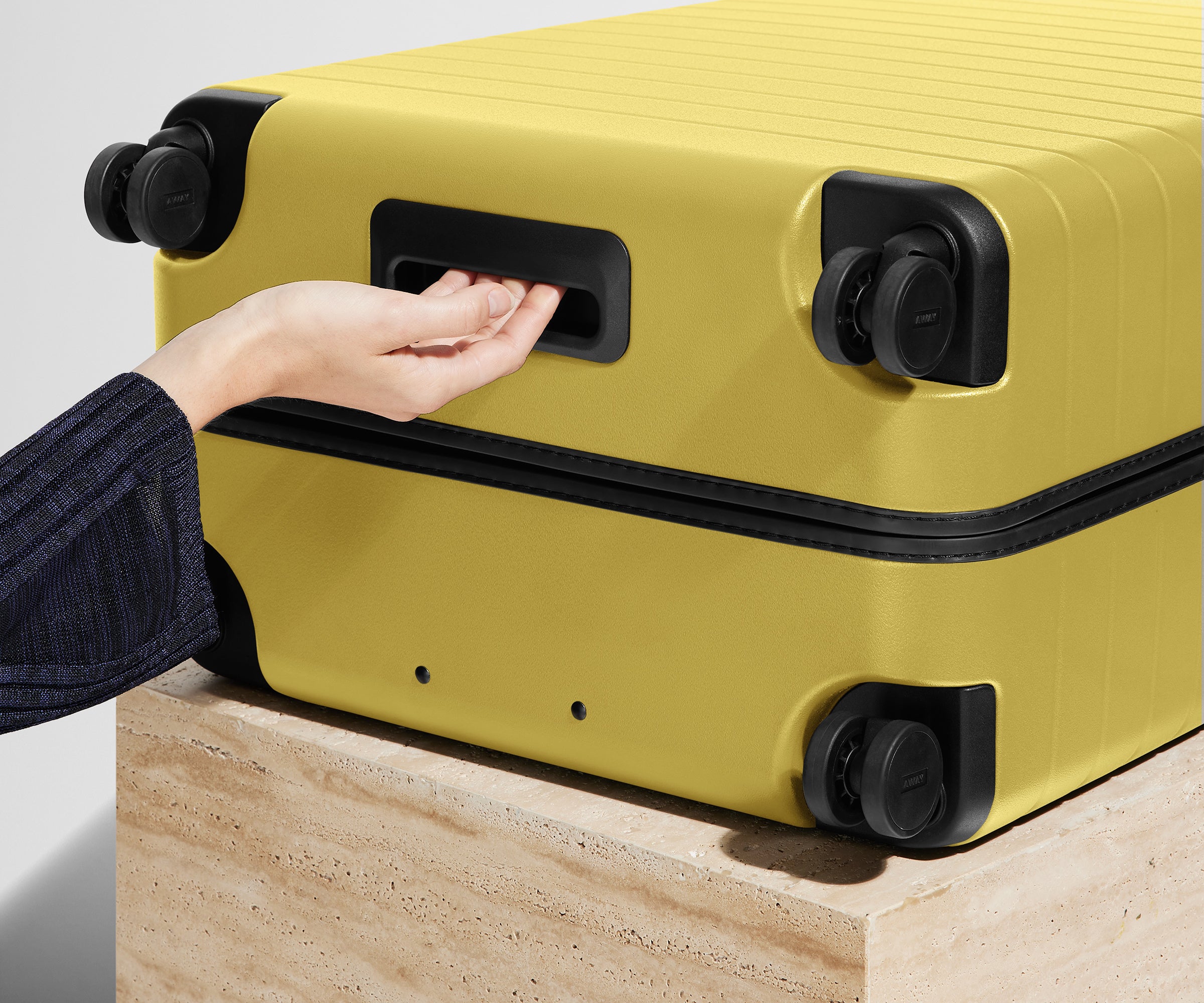 The Large suitcase in Sunshine Yellow shown from below highlighting the underside grab handle