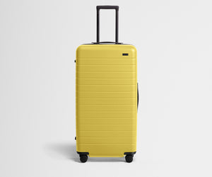 Front product view of The Trunk suitcase in Sunshine Yellow with raised handle