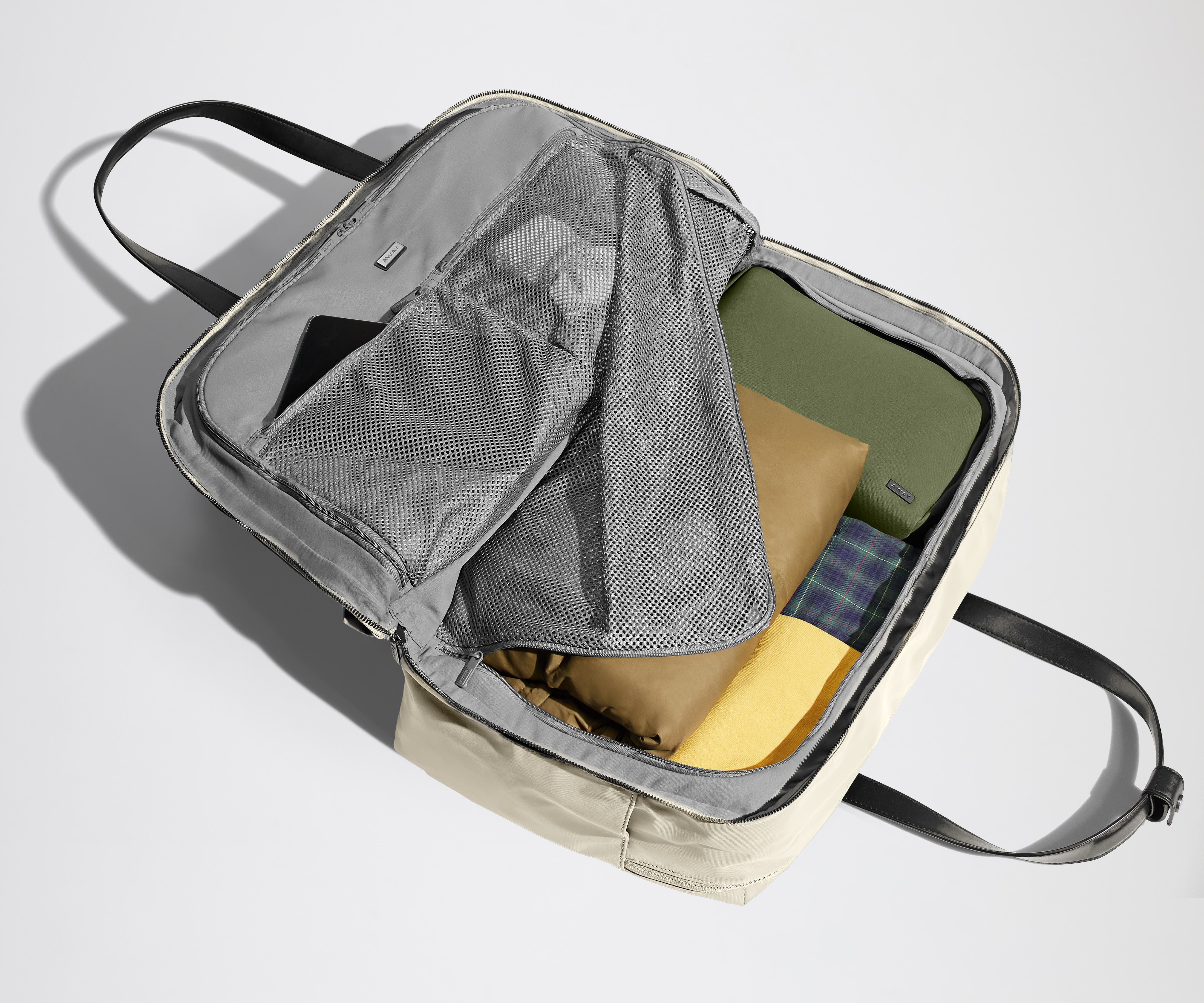 Open clamshell Weekender bag packed with travel essentials, including clothes and Small Toiletry Bag