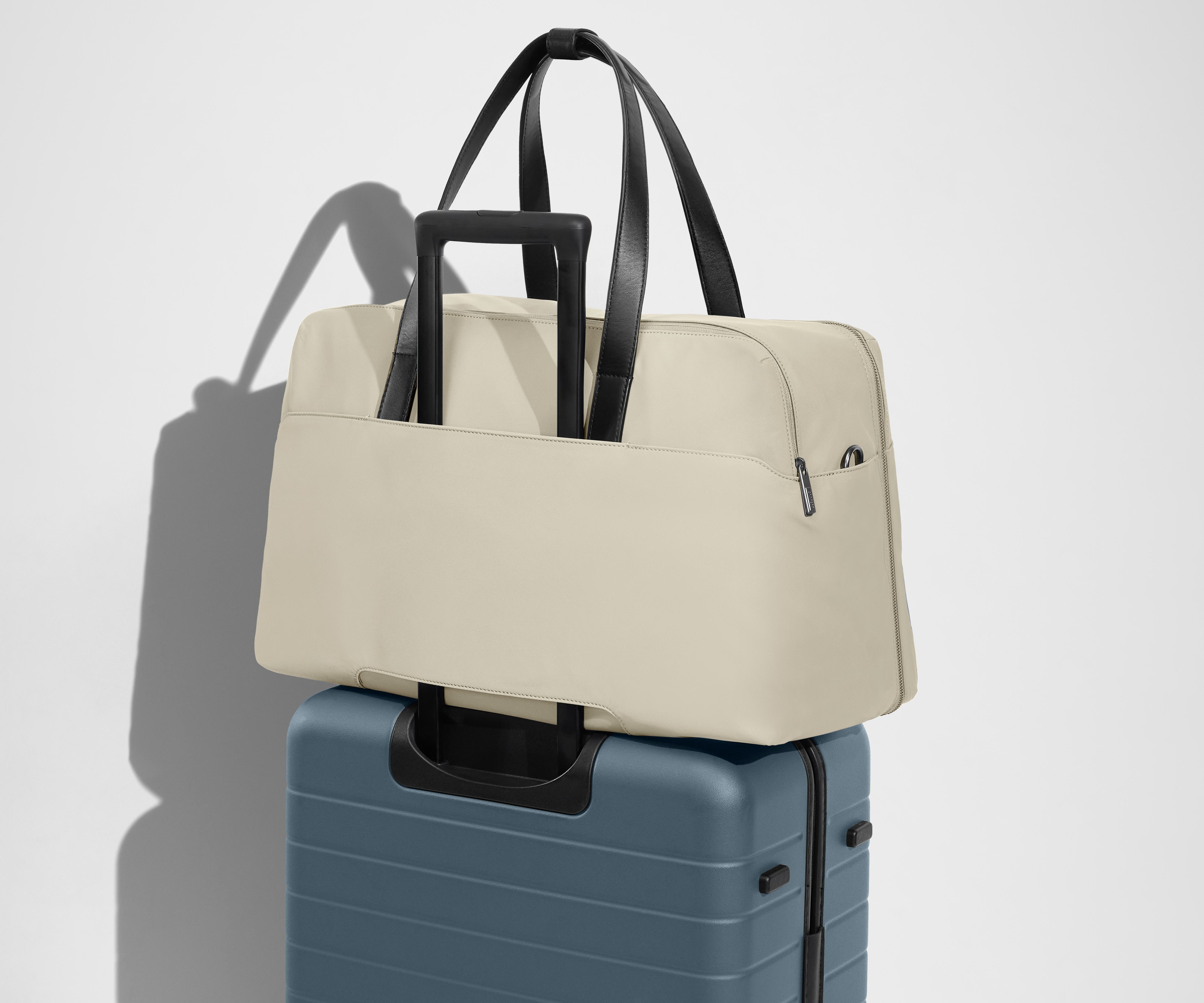Weekender sitting on an Away Large suitcase, using the trolley sleeve pass-through