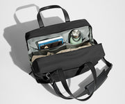 Main compartment packed with a light sweater, notebook, tablet, and water bottle. The detachable shoulder strap is clipped onto the bag.