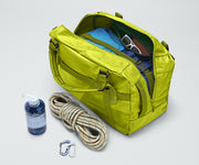 Active Duffle 55L packed with travel essentials and outdoor gear including a packing cube, sunglasses, wallet, carabiner and rope, and water bottle