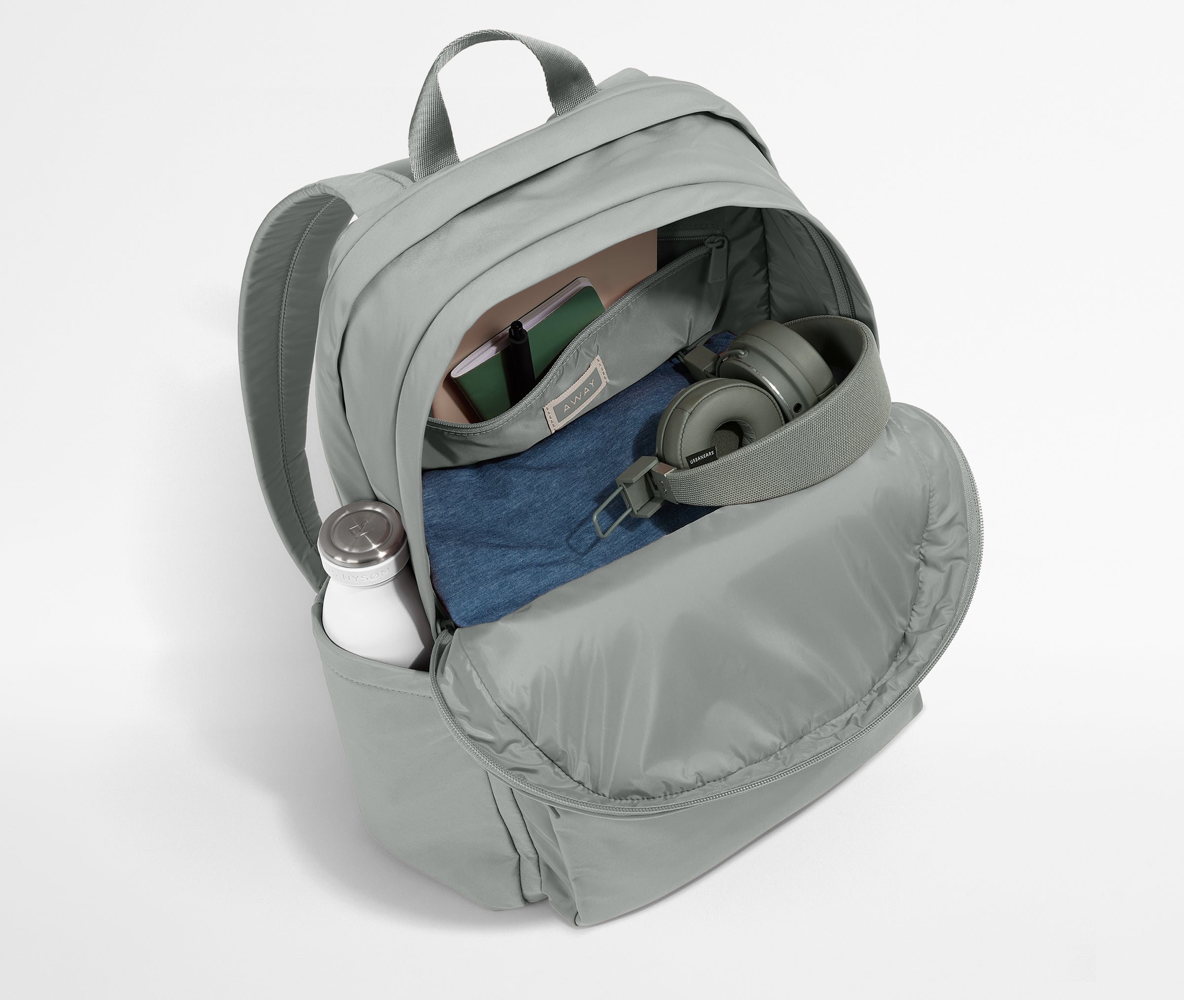 Gray backpack with items like a water bottle and jeans on a white background