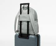 Gray backpack with black handle attached to a suitcase on a light gray background