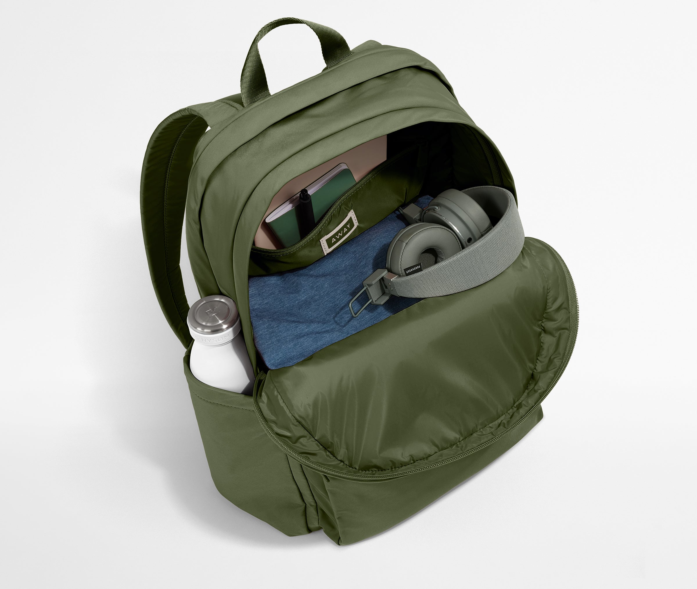 Green backpack with items like a bottle, mask, and headphones on a light gray background