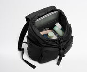 Black backpack with compartments containing a laptop, towel, and bottles on a white background