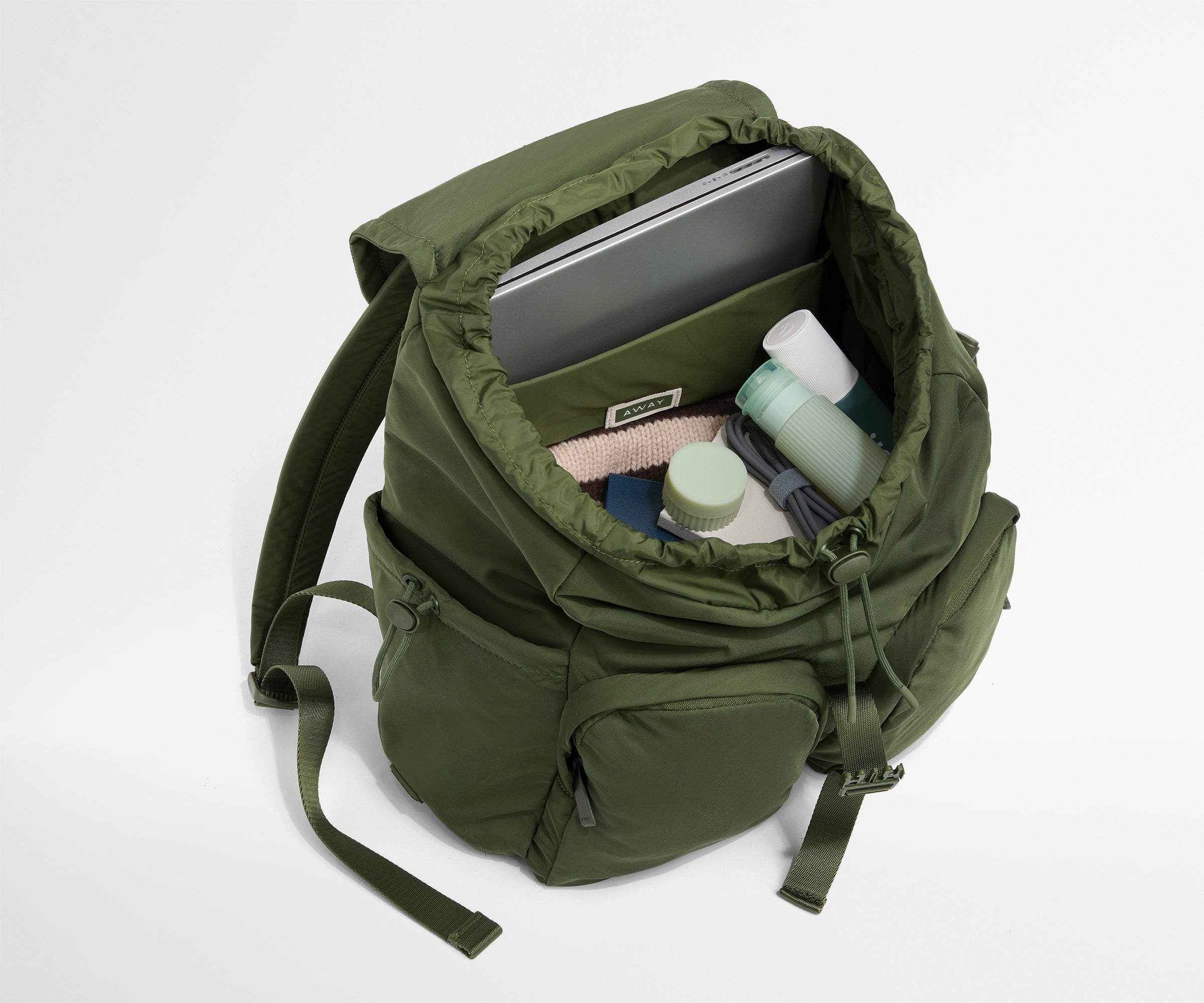 Green backpack with items inside on a white background