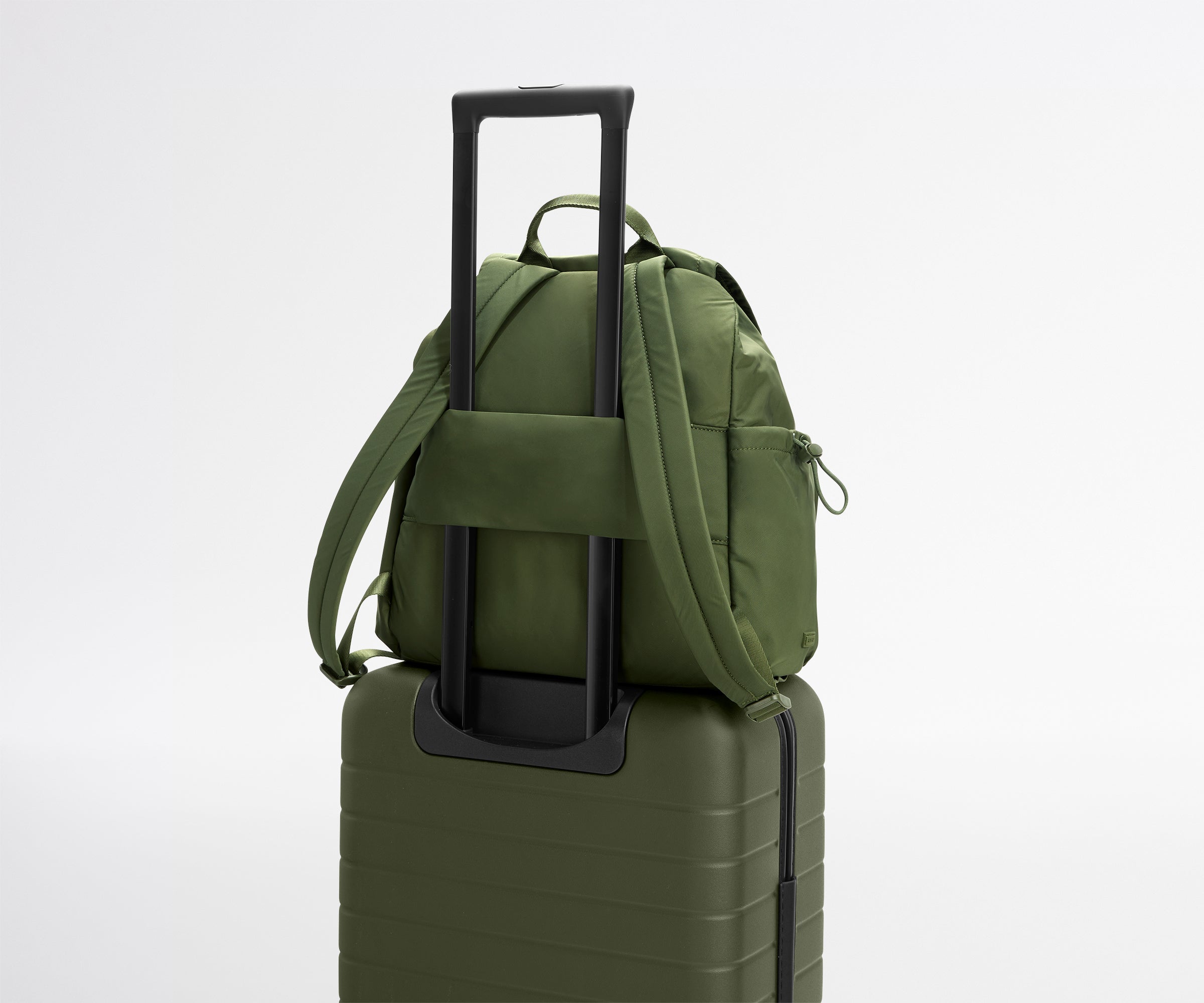 Green backpack on top of a green suitcase with a white background