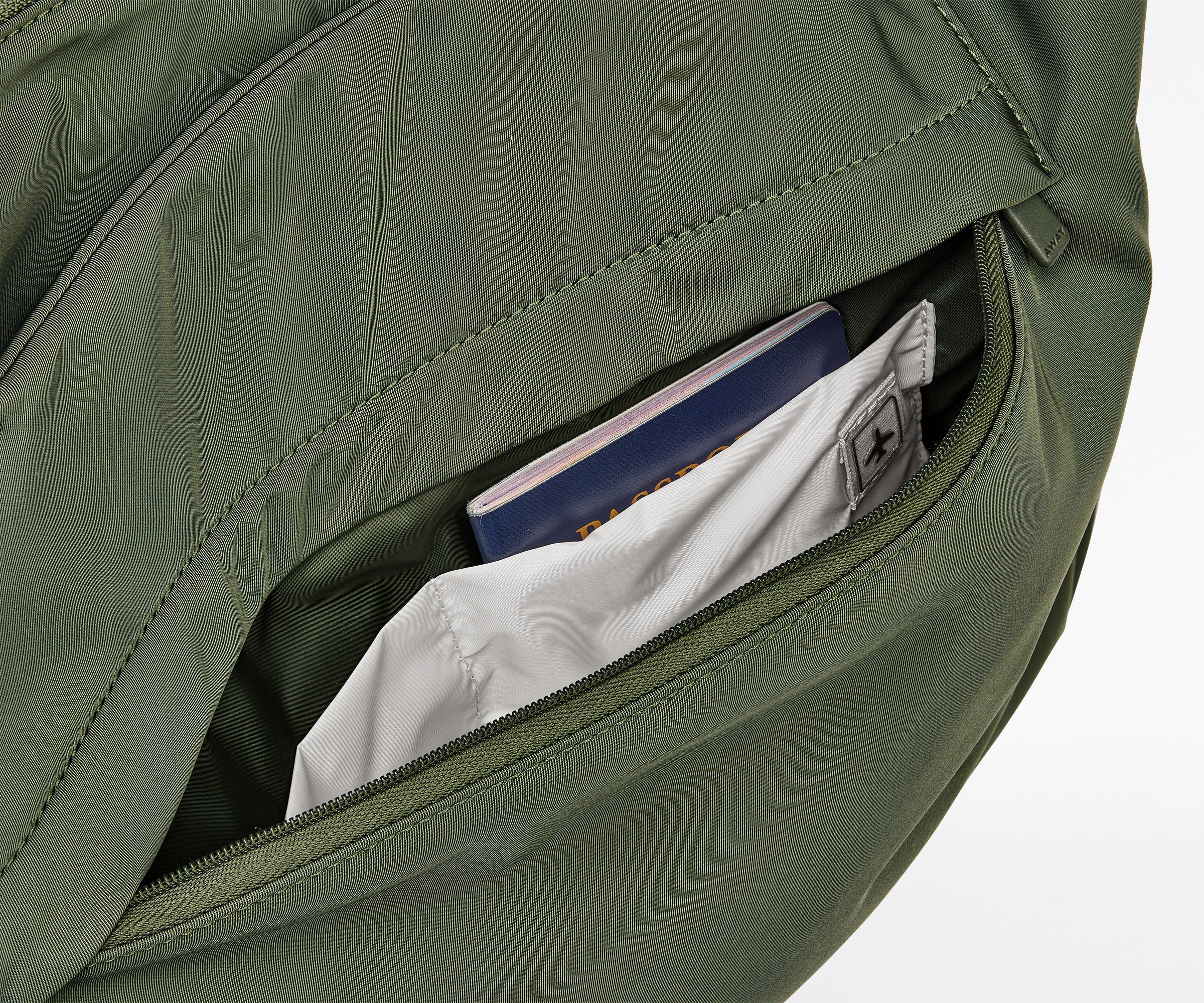 Green backpack with a pocket open, revealing a book and a card inside.