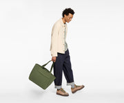 Person holding a green bag on a white background