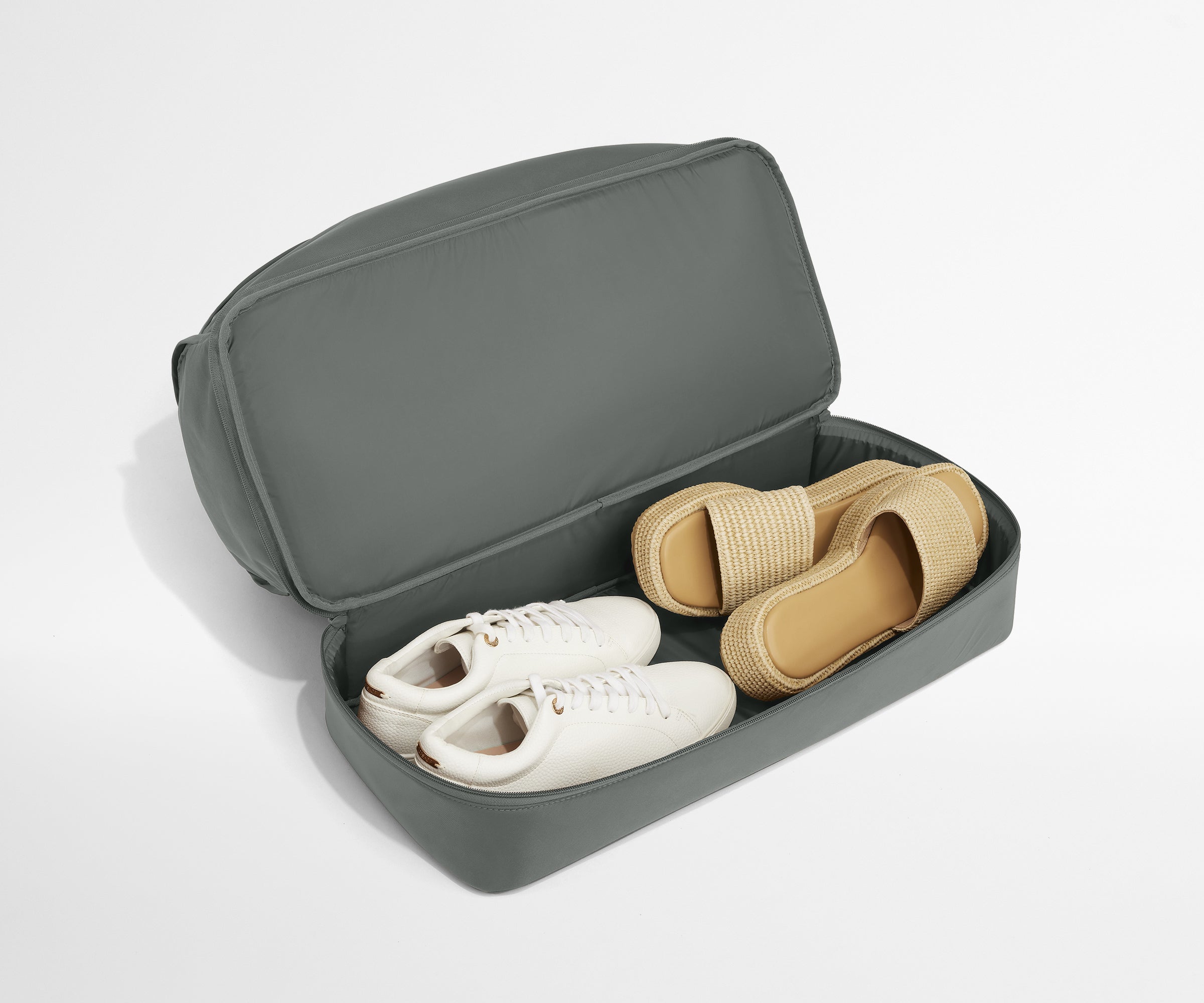 Gray shoe travel case with white sneakers and tan sandals on a light gray background