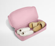 Pink shoe travel case with white sneakers and brown slides inside on a light gray background