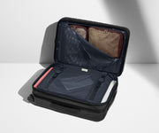 The Bigger Carry-On Flex suitcase in Navy Blue shown open on its side and packed with Away's packing organizers to show capacity and the interior compression system, designed to help you pack more in